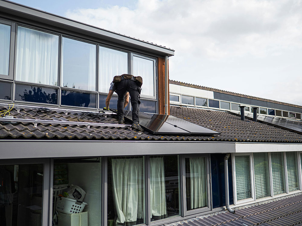 Man on roof working on solar panel